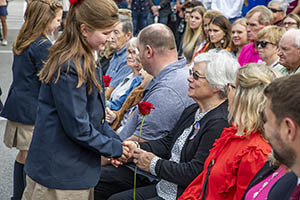 Young girl hands rose to woman